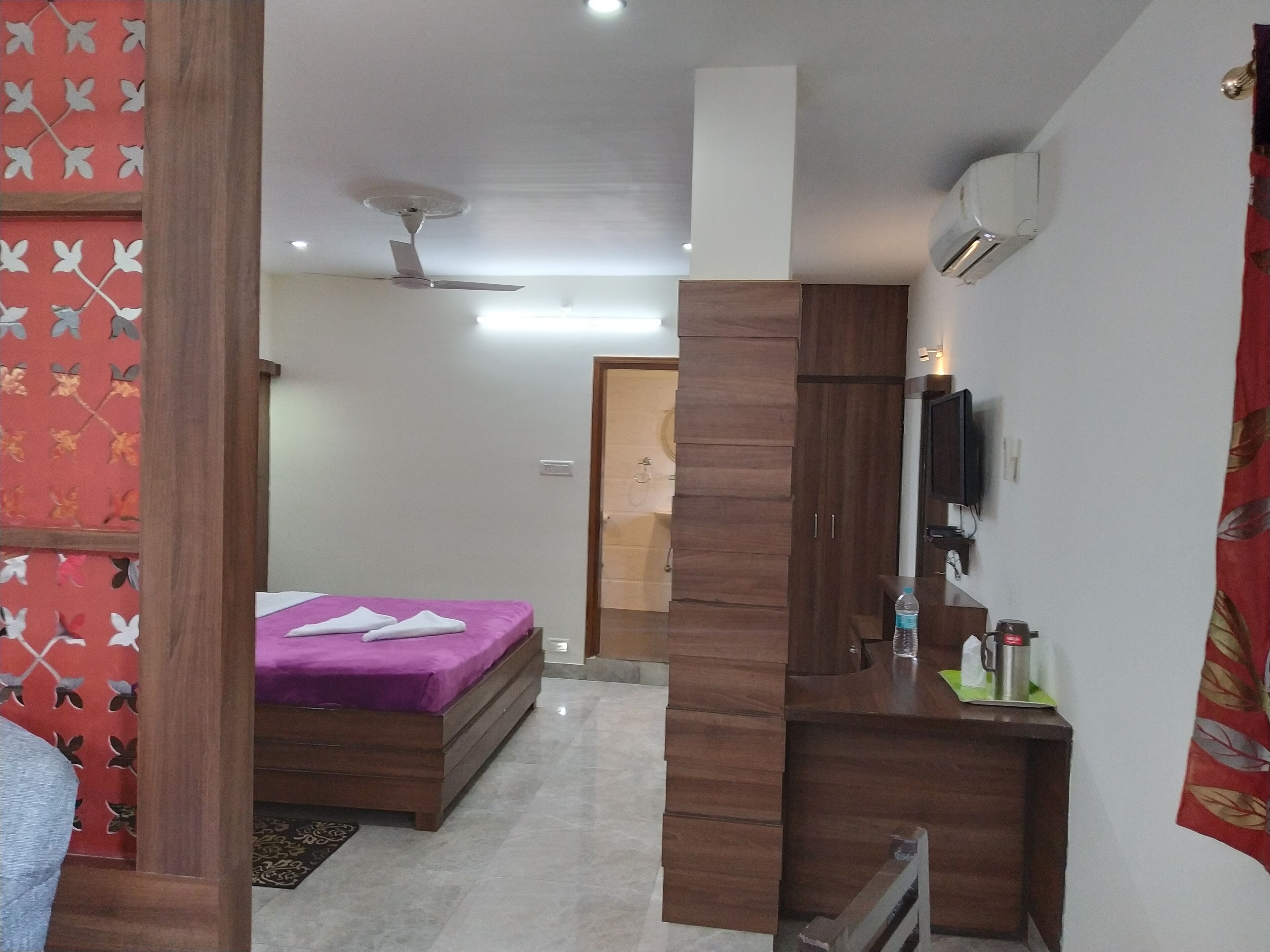 Un dormitorio con cama, un escritorio de madera, un espejo y un ventilador de techo.