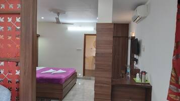 A bedroom with a bed, a wooden desk, a mirror, and a ceiling fan.