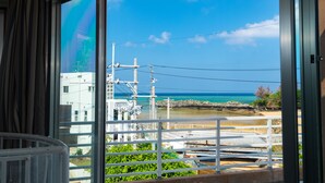 A view from a window overlooking a beach with power lines and buildings in the background. - Lanakai House (Onna)