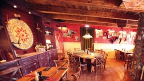 A rustic interior with wooden tables and chairs, a bar area, and a wall clock. - Perfectly equipped apartment1 (Greifswald)