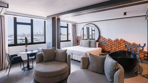 Een moderne hotelkamer met een bed, zithoek, grote ramen en een opvallend wandelement.