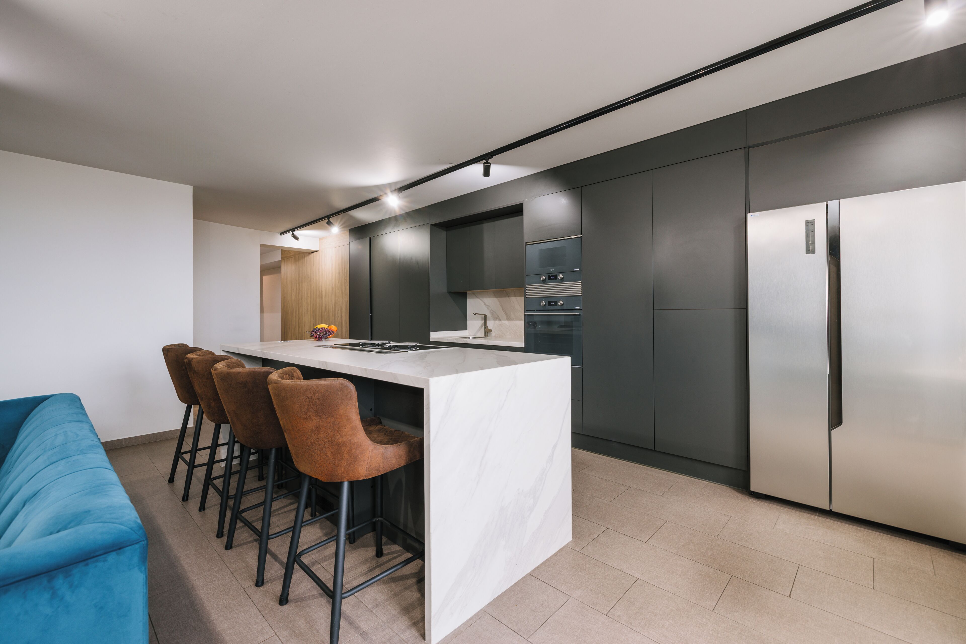 Une cuisine moderne dotée d’un îlot central, de tabourets de bar et d’un four encastré.