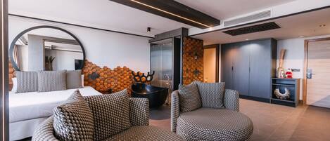 Una sala moderna con sofás estampados, una mesa redonda grande y un diseño de pared hexagonal original.
