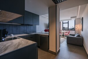 Una cocina moderna con lavavajillas integrado, un comedor con una silla roja y un sofá.