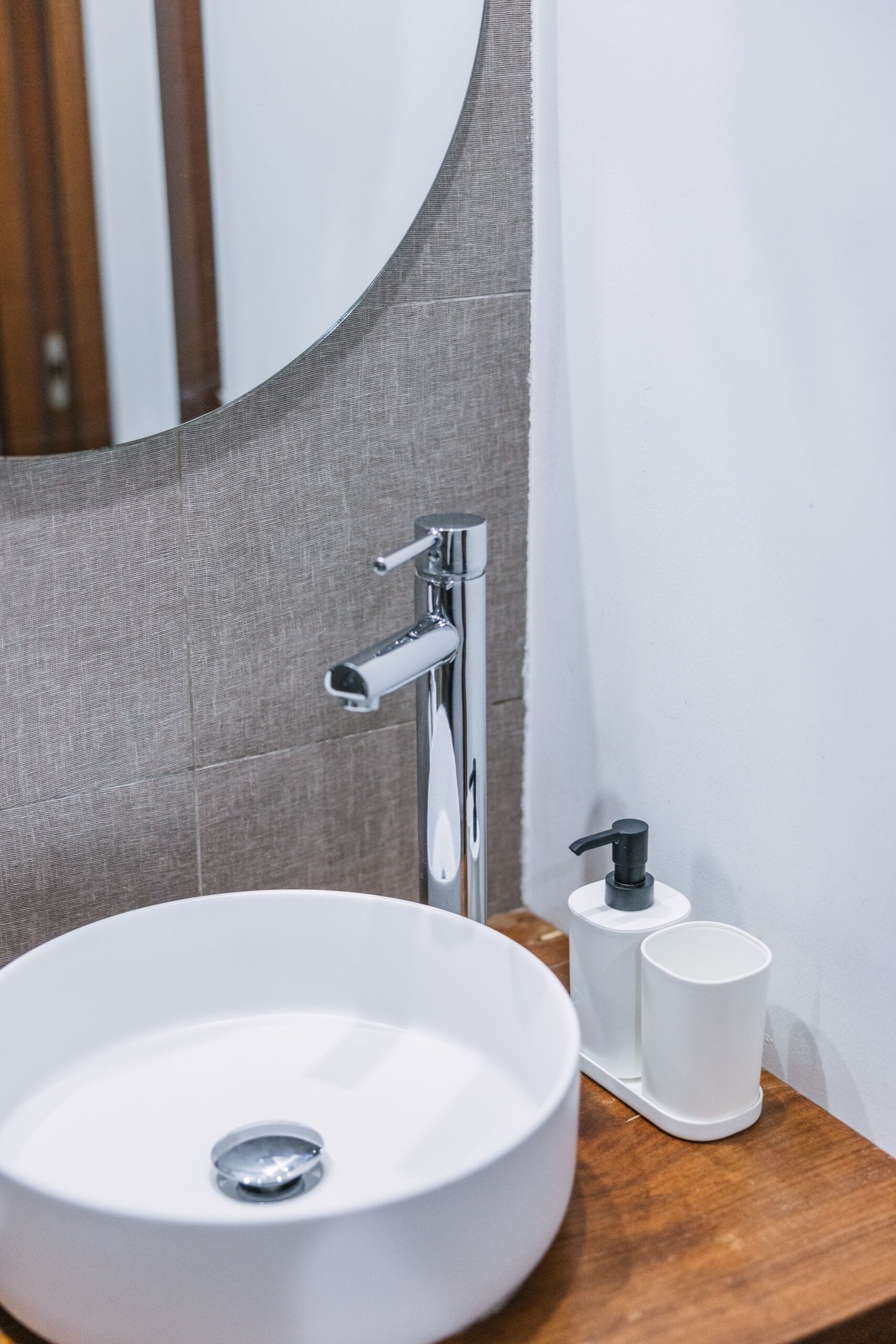 A bathroom with a white sink, chrome faucet, and a mirror.