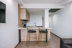 Una cucina moderna con due sgabelli da bar, un piano di lavoro bianco e un forno a scomparsa.