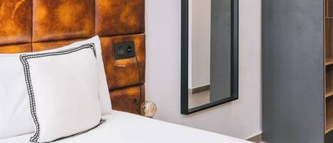 A modern hotel room with a bed, a large mirror, and a built-in wardrobe.