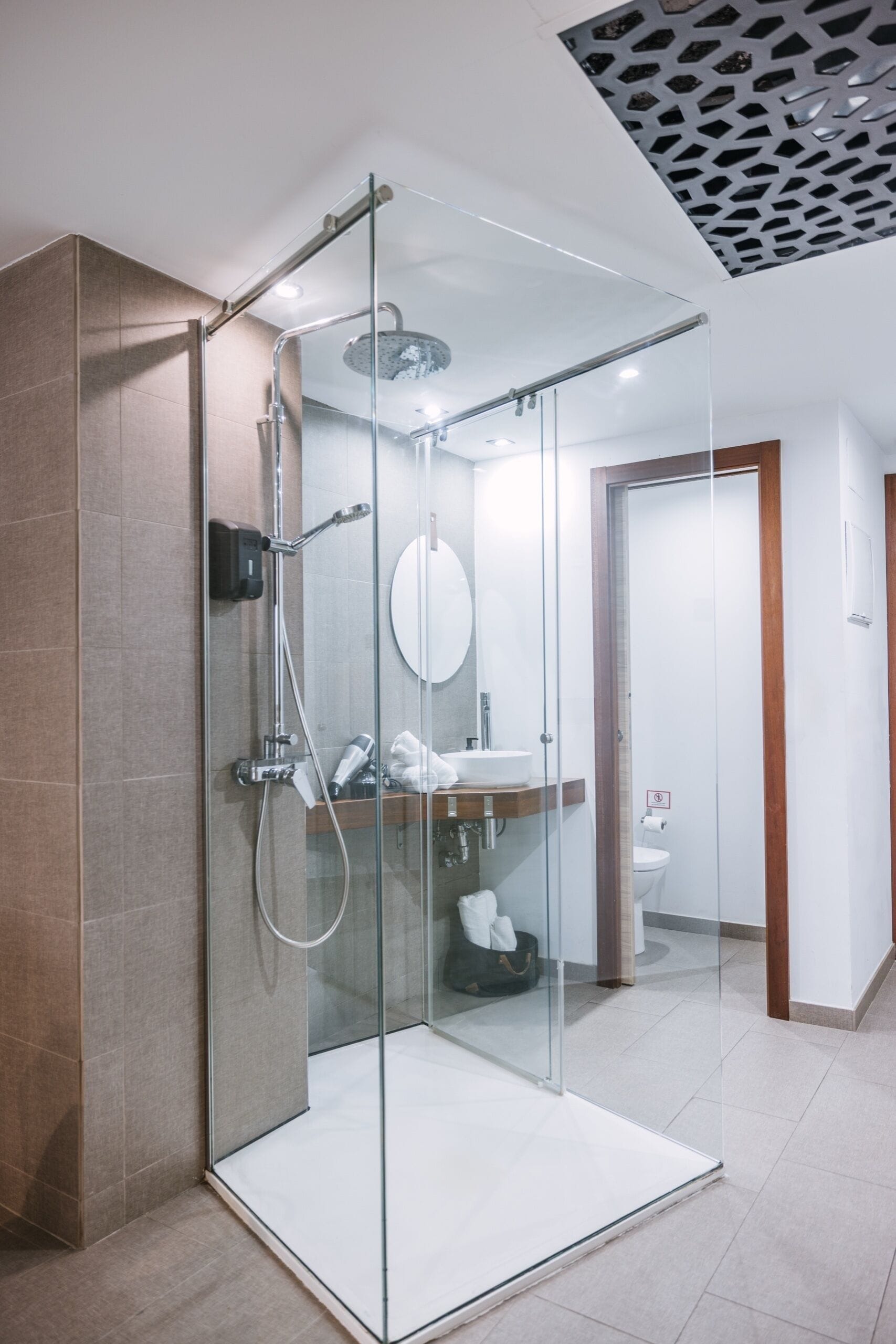 A modern bathroom with a glass-enclosed shower, a sink, and a toilet.