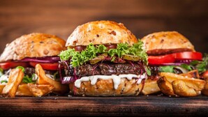 Three burgers with fries and a tomato on a wooden board. - Modern furnished apartment for the family (Greifswald)