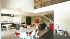 Una cocina moderna con comedor, una escalera y una sala de estar con sofá y sillas rojas.