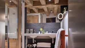 Une salle de bain moderne dotée d’une douche à parois de verre, d’un plafond en bois et d’un lavabo encastré avec un miroir au-dessus.