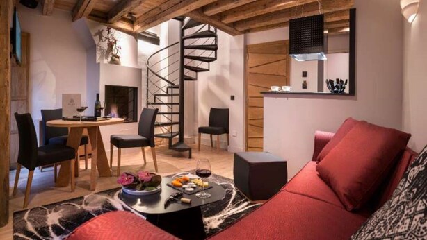 Un intérieur moderne avec un escalier en colimaçon, un coin repas et un espace salon agrémenté d’un canapé rouge.