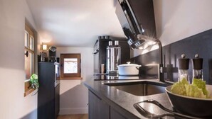 Une cuisine moderne avec un plan de travail noir, une cuisinière, un évier et une fenêtre.