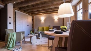 Une pièce chaleureuse avec un plafond en bois, une table à manger ronde entourée de chaises, un canapé et une lampe.