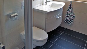 A bathroom with a toilet, sink, and glass shower enclosure. - Apartment for a maximum of 5 persons (Greifswald)