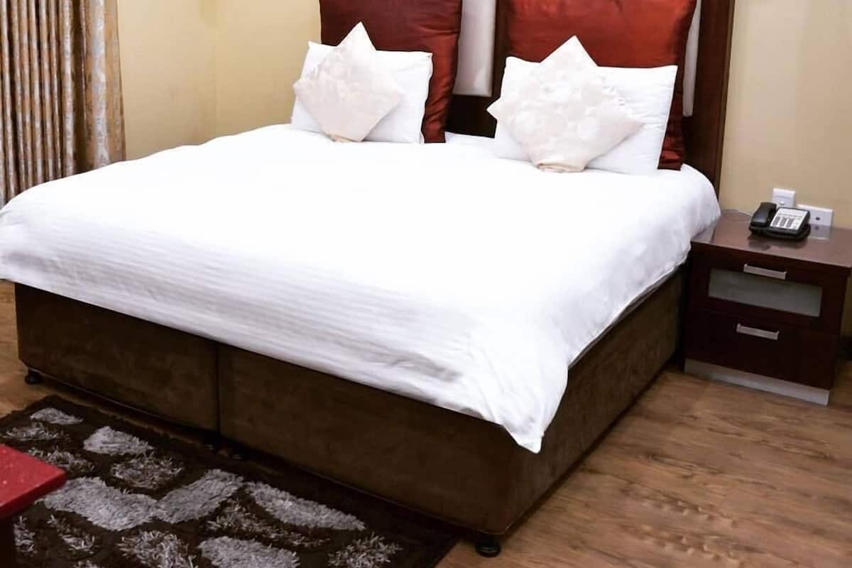 Hotellihuone, jossa on suuri sänky, kaksi yöpöytää, puhelin ja lamppu kummassakin yöpöydässä.