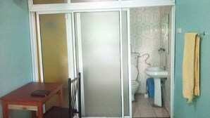 A small bathroom with a toilet, sink, and a chair. - Sweet Hut Hotel (Marua)