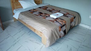 A single bed with a wooden headboard, a patterned bedspread, and a white pillow. - Sweet Hut Hotel (Marua)