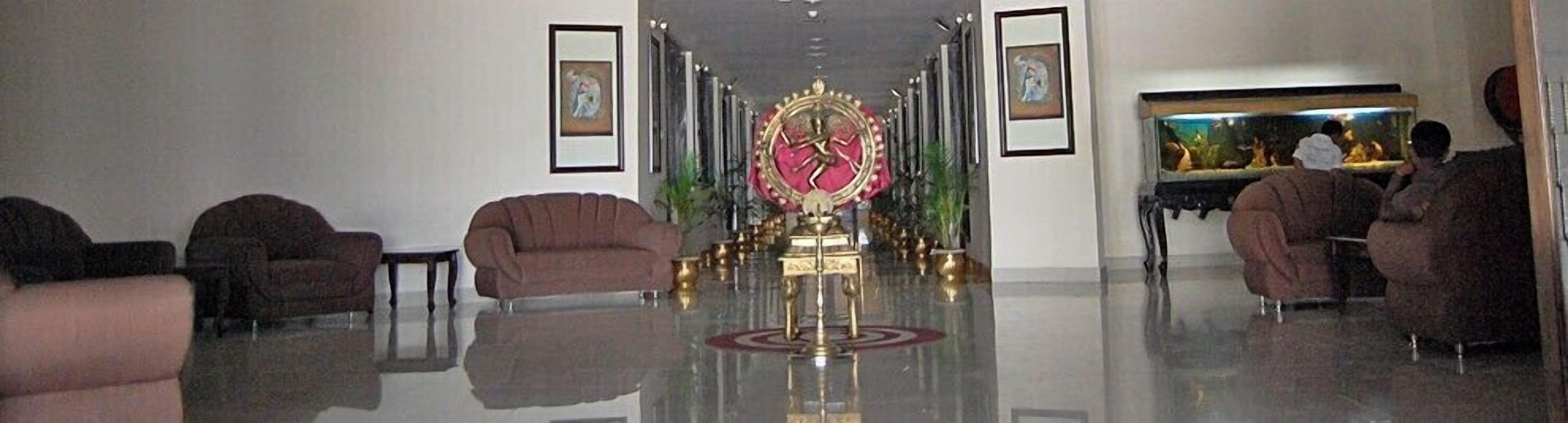 A lobby with a central ornate golden statue, flanked by sofas and framed artwork on the walls.