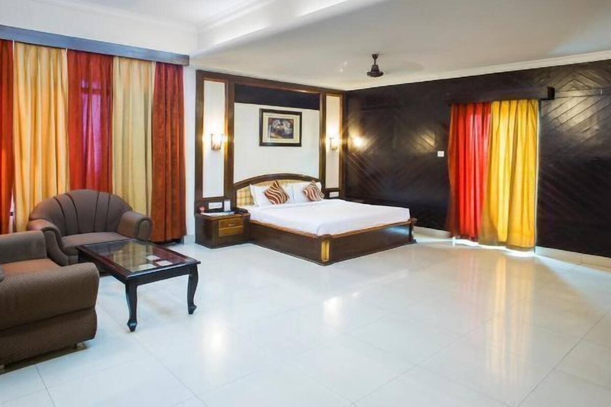Ein Hotelzimmer mit Bett, Sofa, Nachttisch und Schreibtisch.