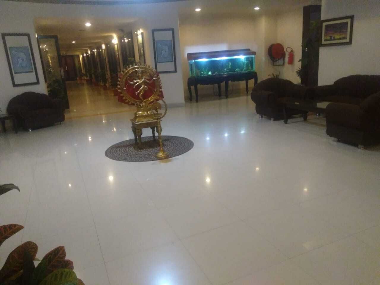 A spacious lobby with a central decorative fountain, a grand piano, and comfortable seating areas.
