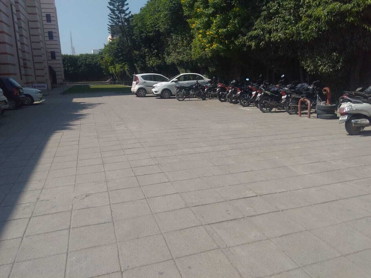 A parking lot with several cars and motorcycles parked.