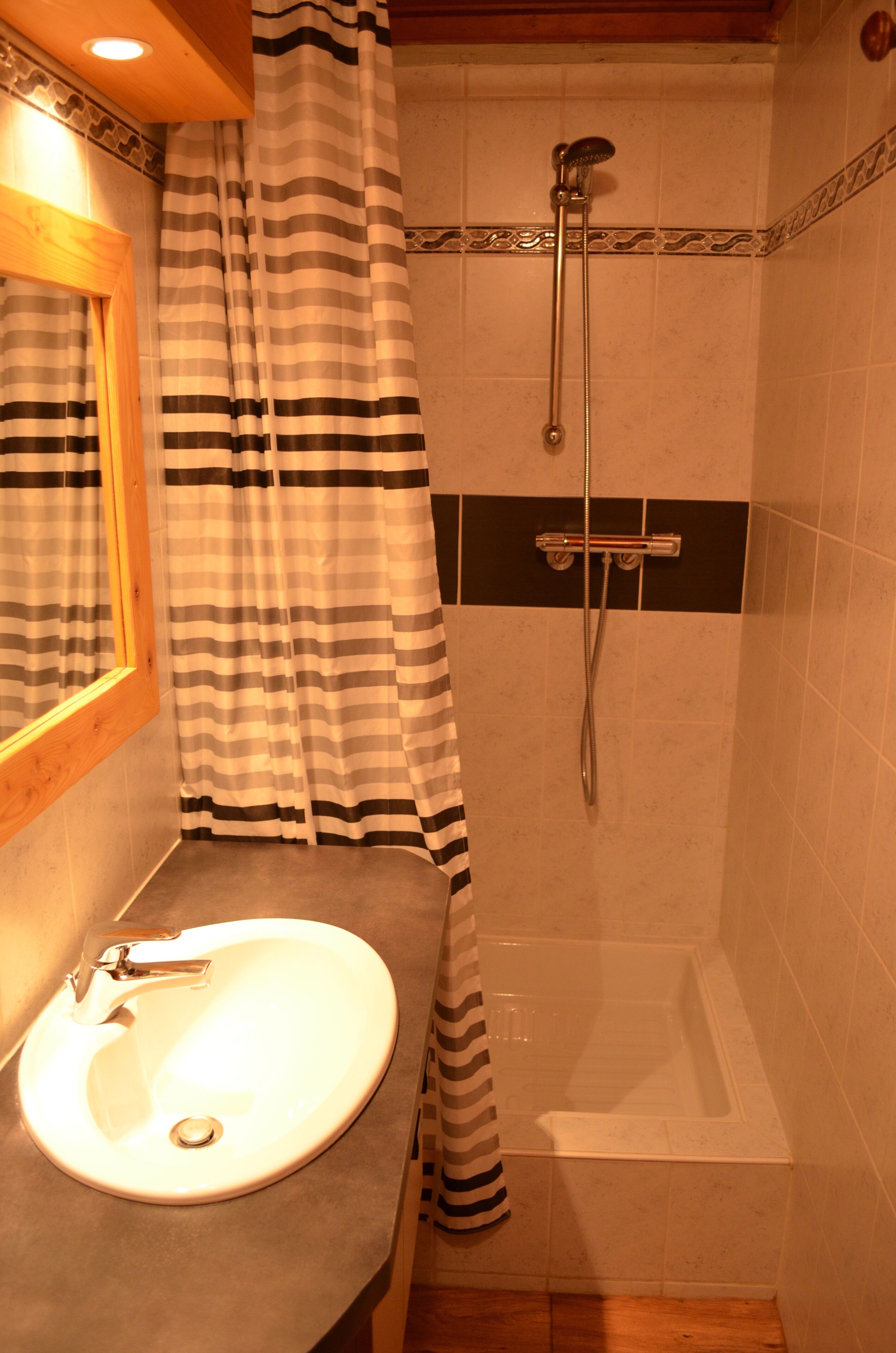 Une salle de bain avec un lavabo, une douche et des rideaux à rayures.