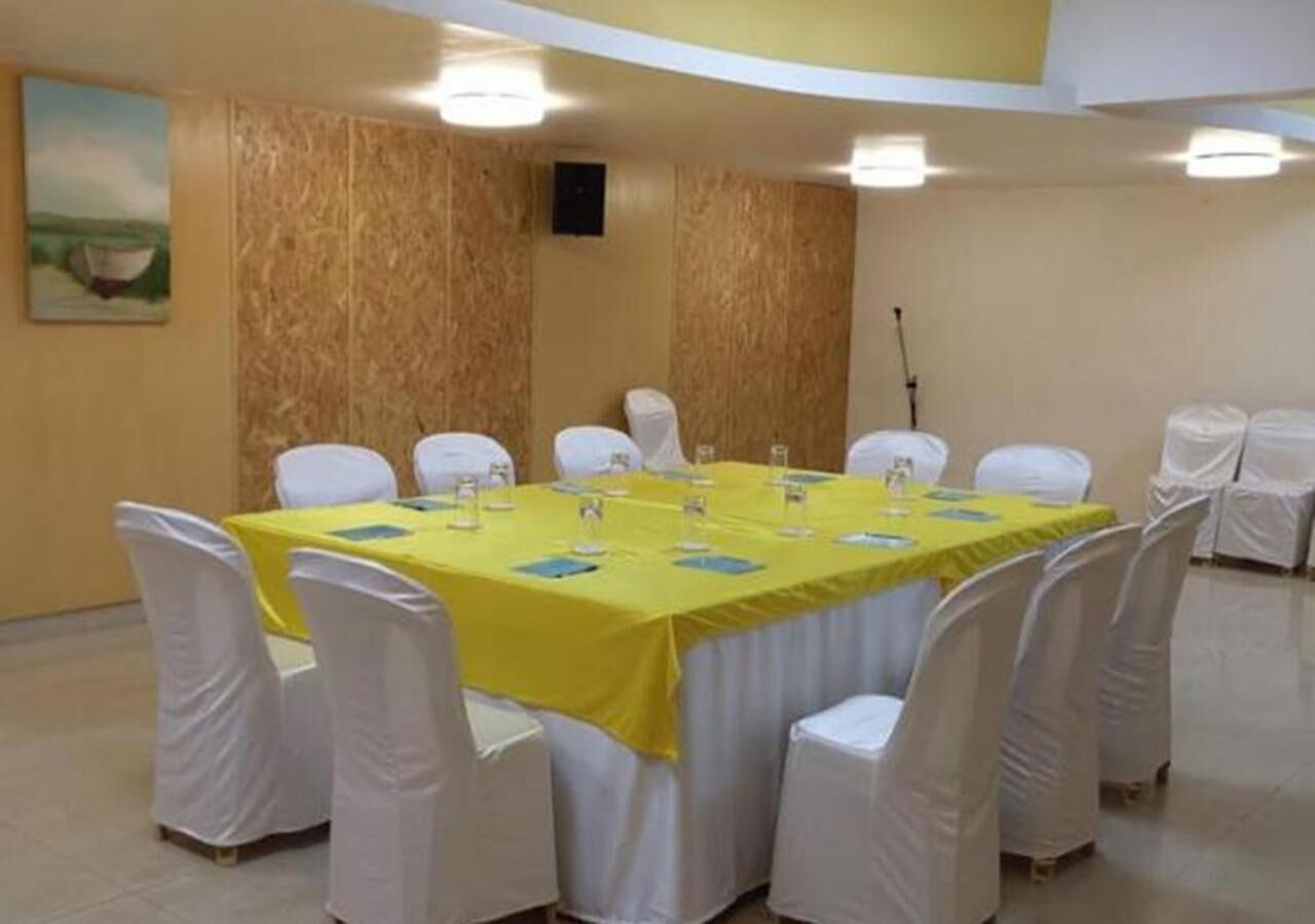 Ein Konferenzraum mit gelbem Tisch, weißen Stühlen und einer Wand aus Holzverkleidung.