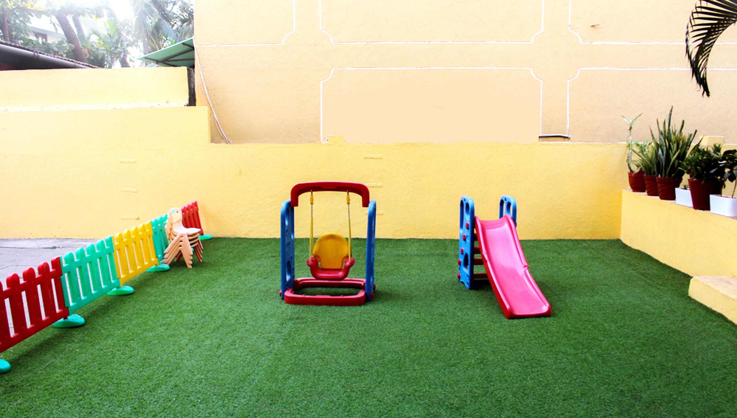 Un espace de jeux pour enfants avec des balançoires, un toboggan et un petit coin salon.