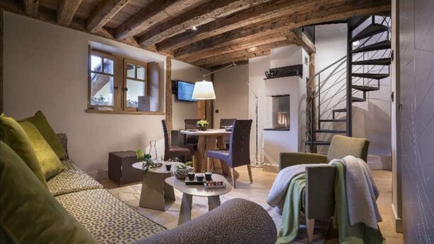 Una sala de estar acogedora con un sofá, una mesa de centro y un televisor. Se ve una escalera que sube a un nivel superior.