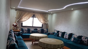 A living room with a sectional sofa, two round tables, and a large window with curtains. - Quiet residence "Perla" (Bousnika)