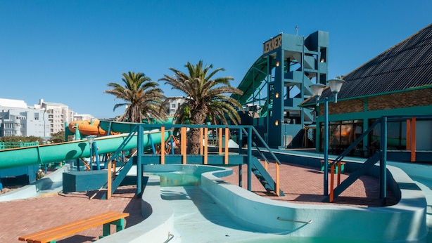Un parc aquatique doté de toboggans et d’une zone de piscines, entouré de palmiers et de bâtiments.