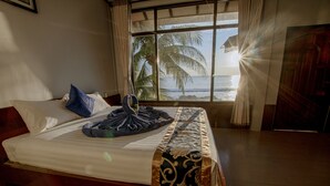 Ein Hotelzimmer mit Bett, Fenster mit Meerblick und Holzboden.