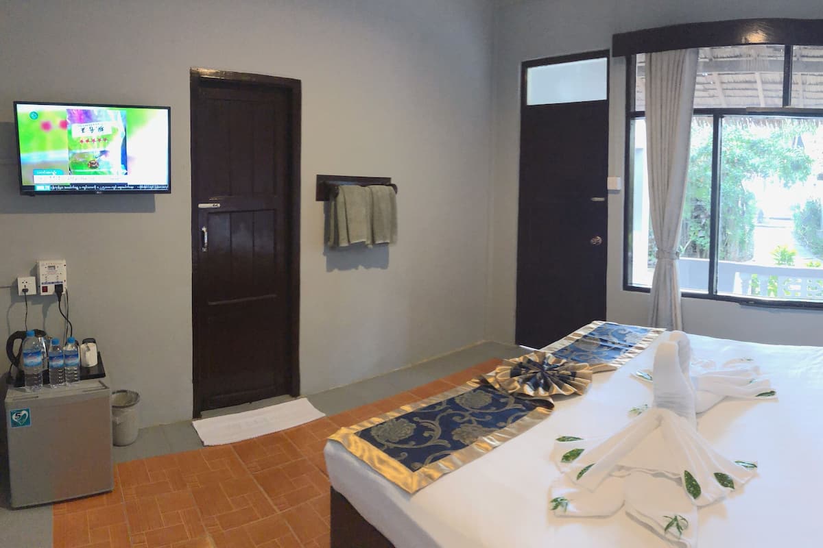 Hotelkamer met een bed, een televisie, een minibar en een raam met gordijnen.