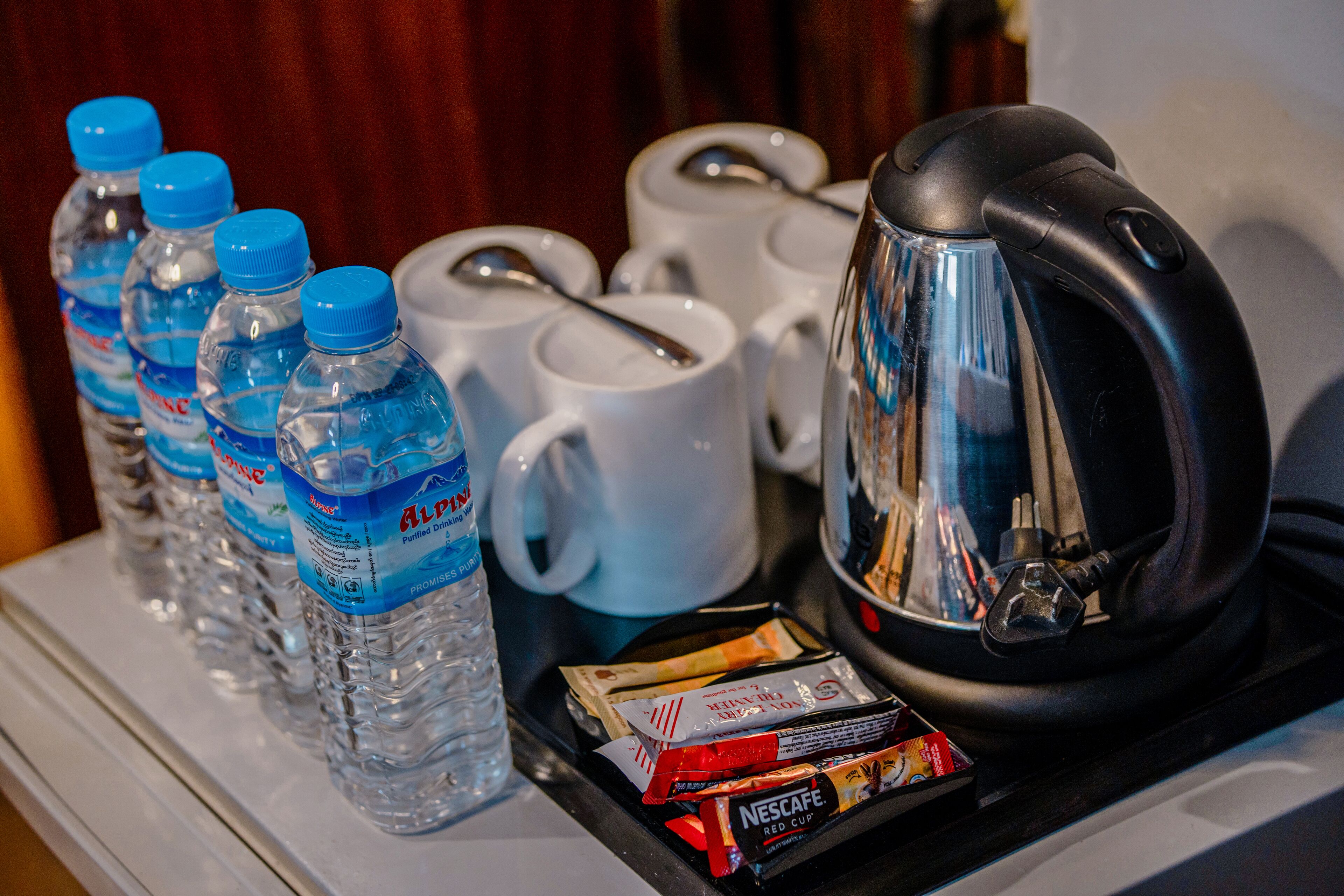 A tray with water bottles, coffee mugs, a coffee pot, and some food items.