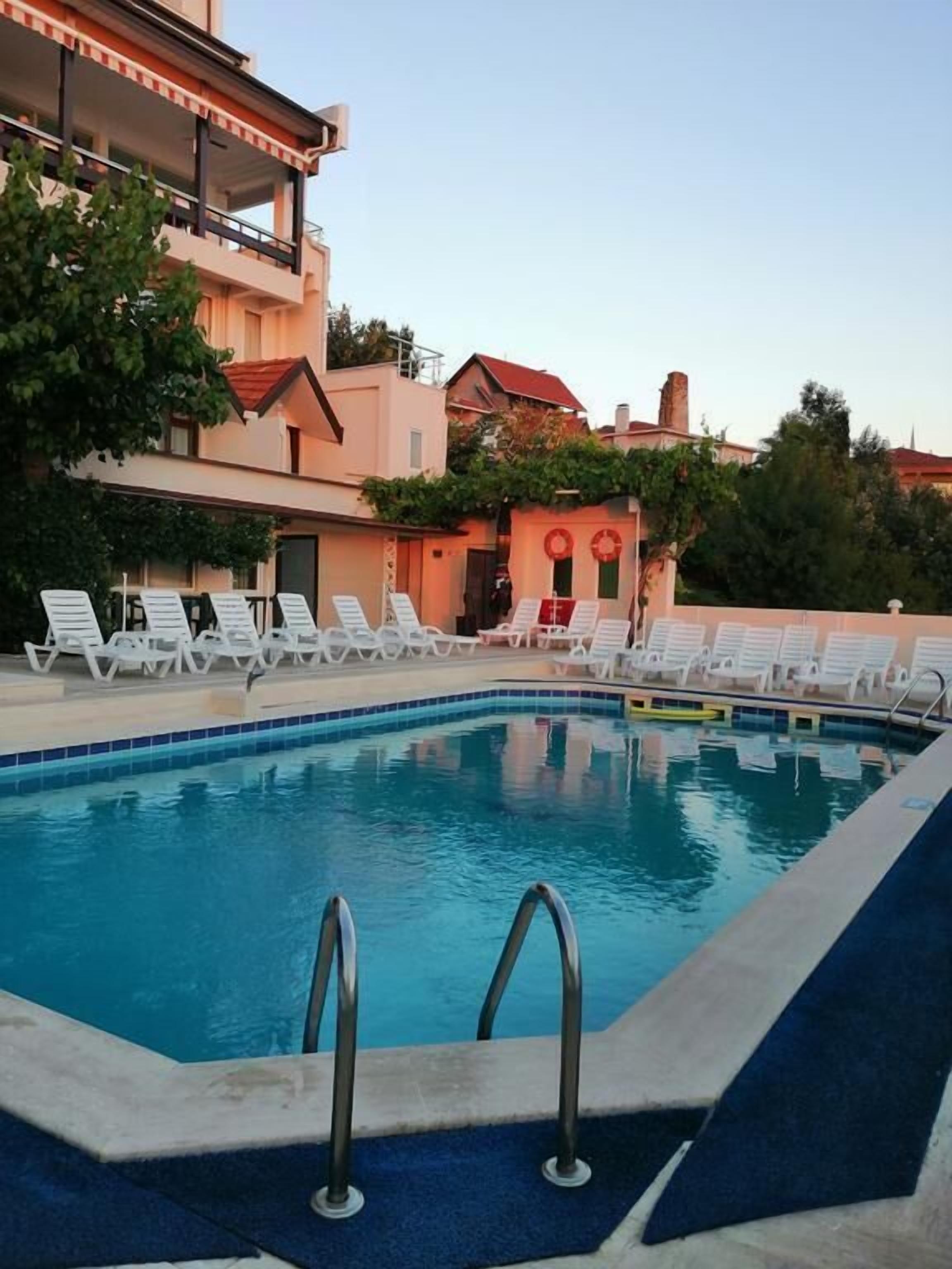 Una piscina con sillones de descanso y un edificio al fondo.