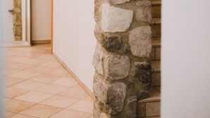 A stone staircase with a wooden handrail leading to a door with a light switch. - Gästehaus Richter (Grainau)