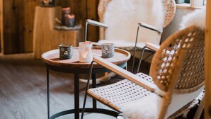A cozy room with a round table, two wicker chairs, and hanging light fixtures. - Gästehaus Richter (Grainau)