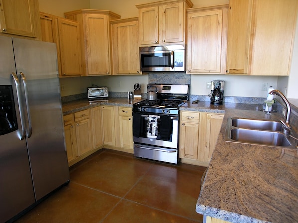 Enjoy cooking and meal prep in this well-equipped kitchen with a stainless steel refrigerator, double sink, and ample storage.