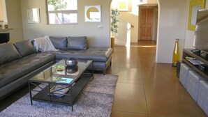 A modern living room with a grey sofa, a glass coffee table, and a TV on a wooden stand. - Popular West Sedona Home! 3BR 3BA, All Nearby! (Sedona)