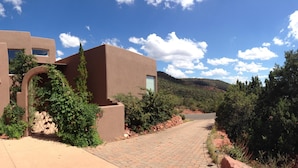 A modern building with a flat roof, a garage, and a paved driveway leading to a road. - Popular West Sedona Home! 3BR 3BA, All Nearby! (Sedona)