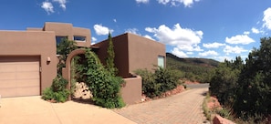 Stucco-clad home with a flat roof, surrounded by landscaped gardens and a paved pathway.