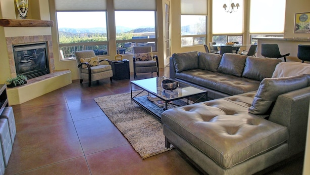 A spacious living room with a fireplace, comfortable seating, large windows, and a view of the outdoors. - Popular West Sedona Home! 3BR 3BA, All Nearby! (Sedona)
