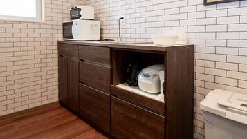 Une cuisine équipée d’un four à micro-ondes, d’une machine à café et d’une poubelle.