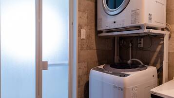 A compact laundry room with a front-loading washer and dryer, a towel rack, and a door leading to a balcony.