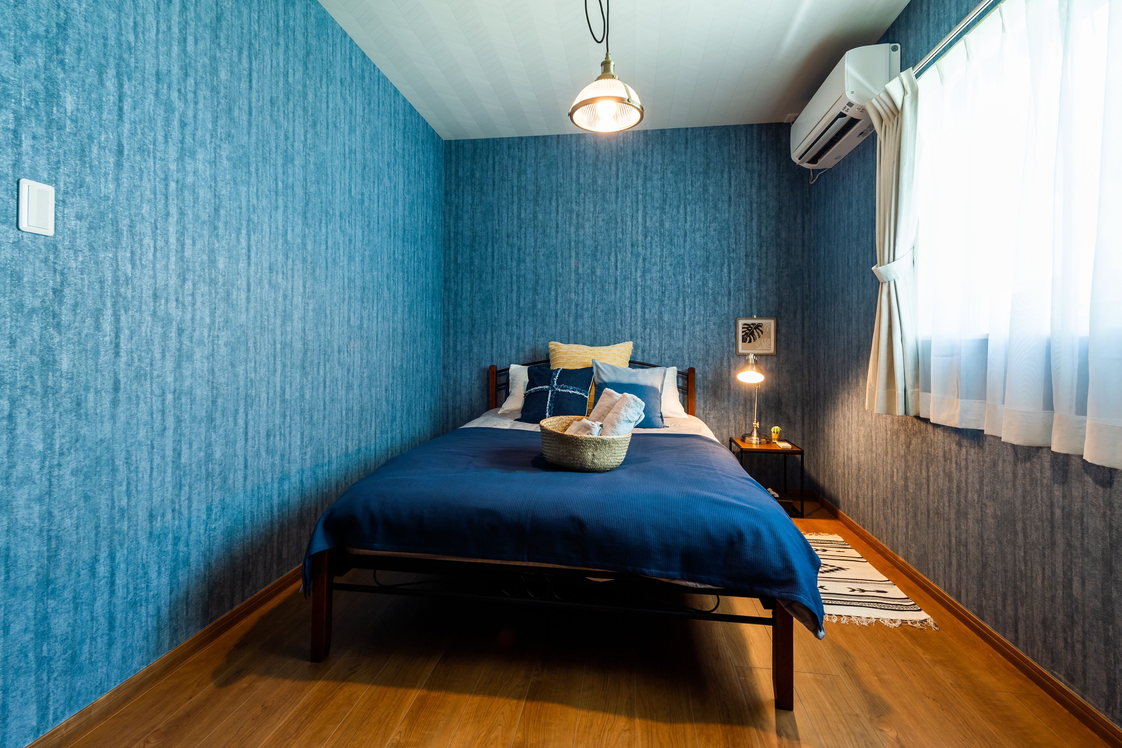 A room with a bed, a nightstand, a lamp, and an air conditioning unit.