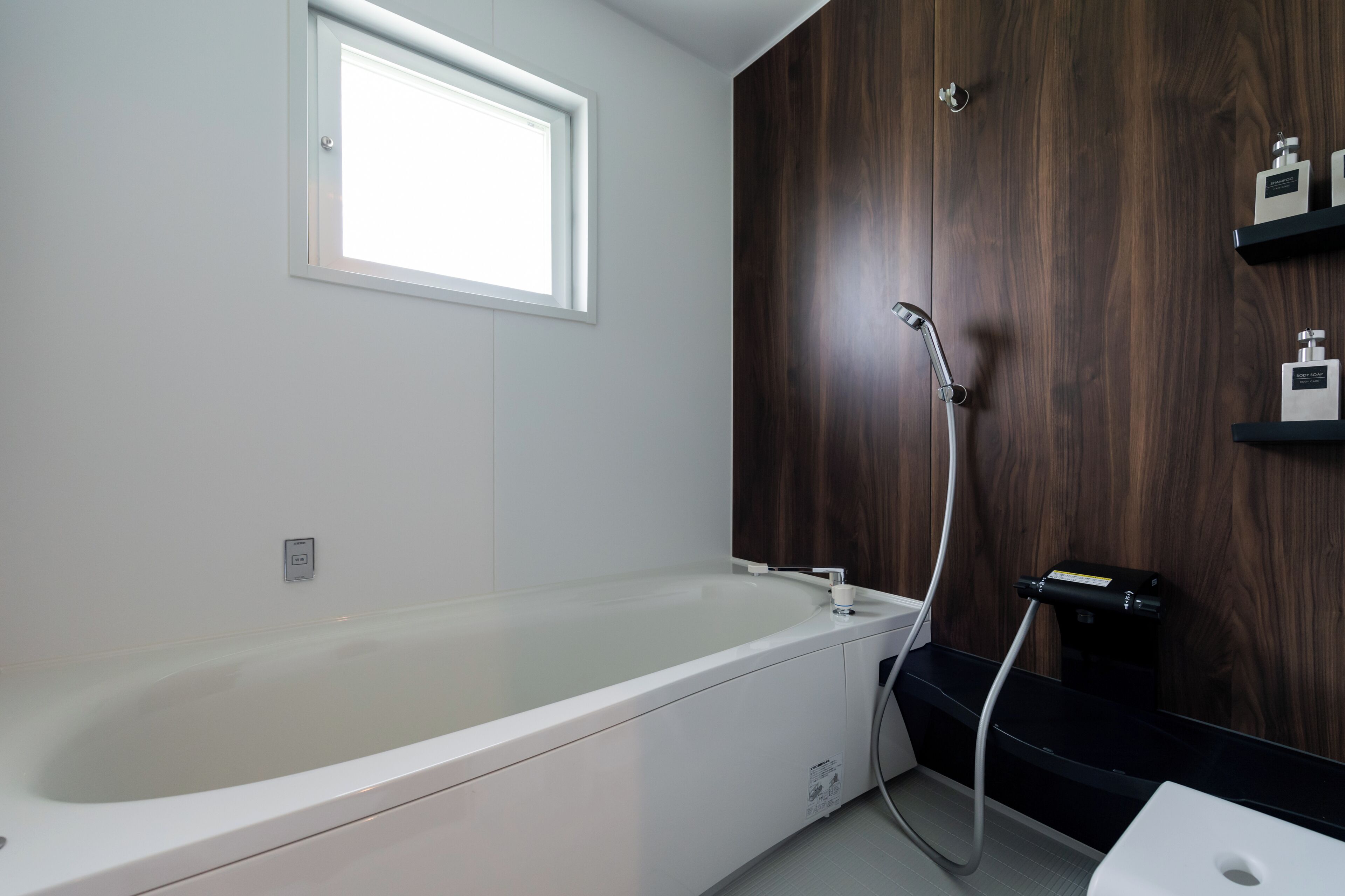 A modern bathroom with a large bathtub, a shower, and a window.