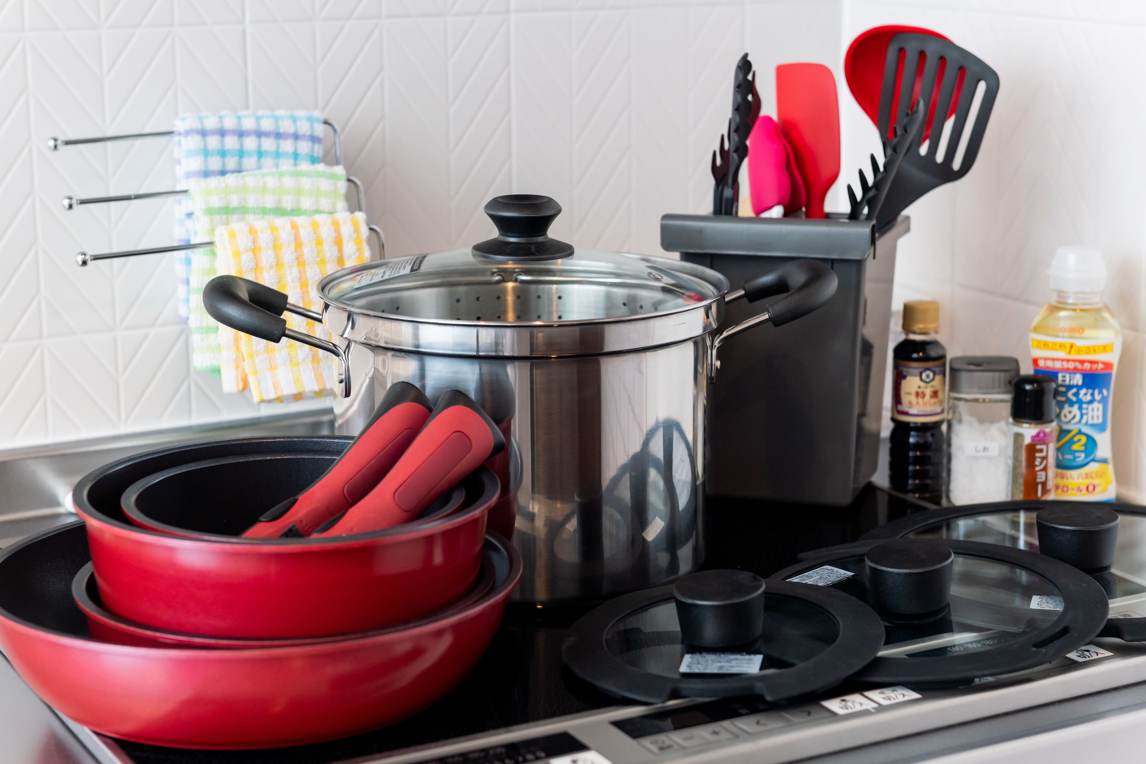 A kitchen with a stove, pots, pans, and various utensils.