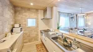 Een moderne keuken met een spatwand van natuursteen, roestvrijstalen apparatuur en een houten aanrecht.