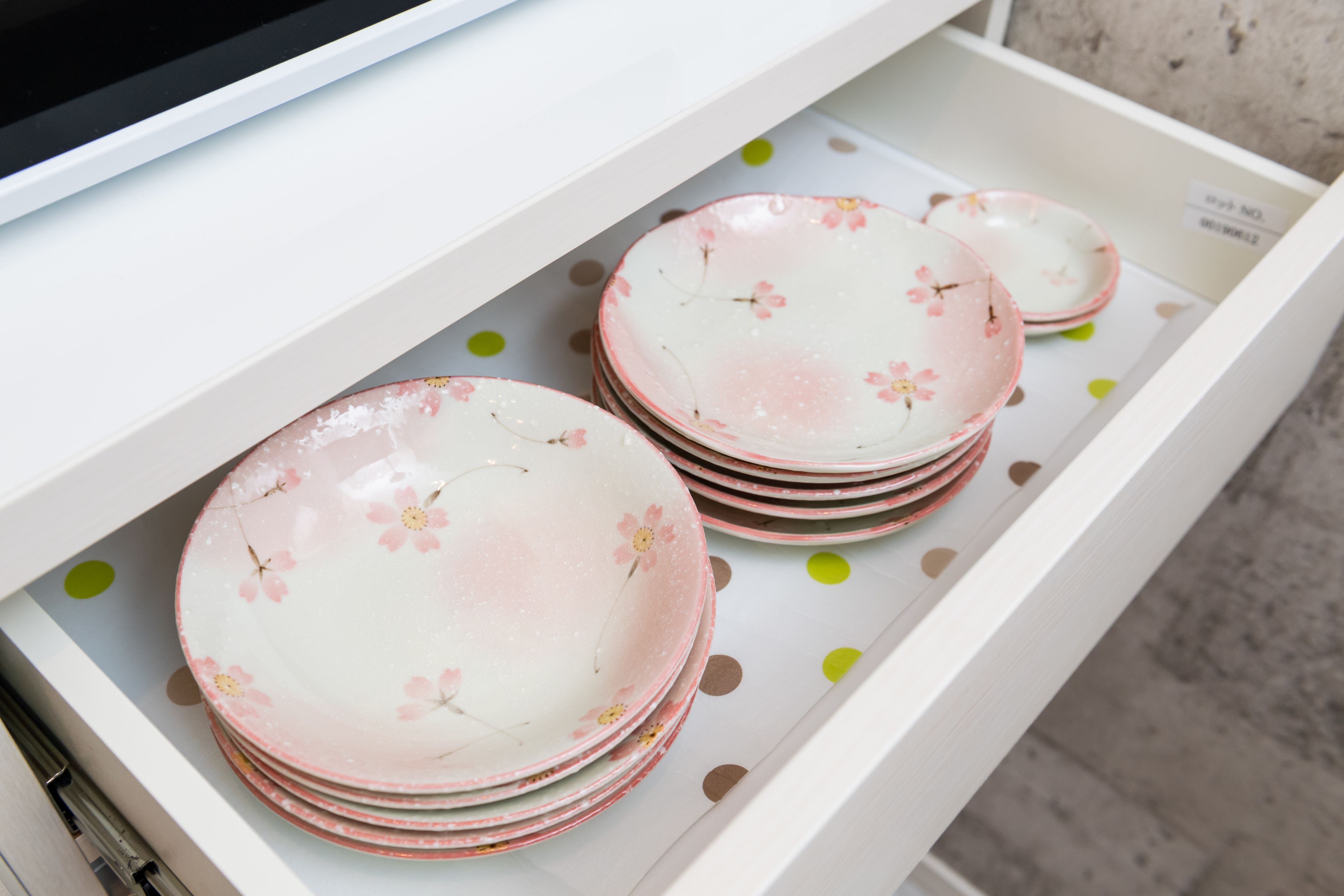 A drawer containing stacks of pink plates with floral designs.